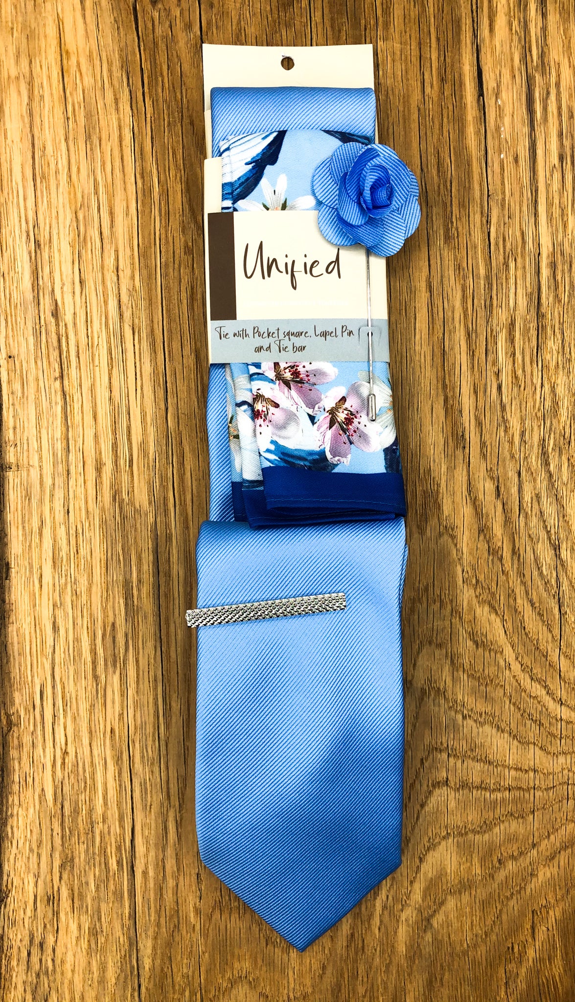 Men's sky blue tie, blue floral pocket square, lapel pin and tie bar